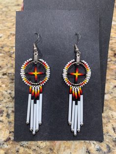 two pairs of beaded earrings with cross on them sitting on a table next to a card