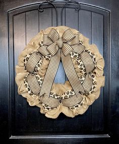 a black door with a leopard print wreath hanging on it's side and an animal print bow at the top