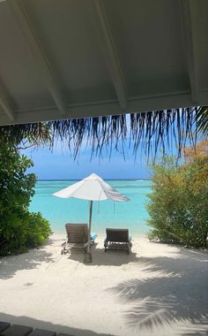 two lawn chairs under an umbrella on the beach