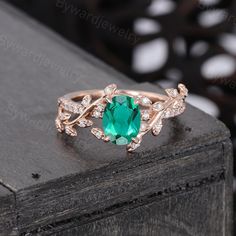 a ring with an oval cut green stone surrounded by small white diamonds on a wooden surface