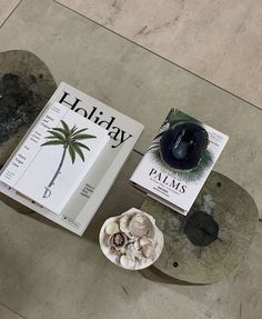 two books are sitting on top of a coffee table with a bowl of seashells