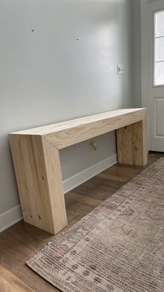 a large wooden bench sitting on top of a hard wood floor next to a rug