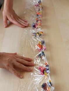 someone is making a long line of candy wrappers on top of a wooden table