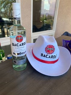 a white hat sitting on top of a table next to a bottle of bacardi