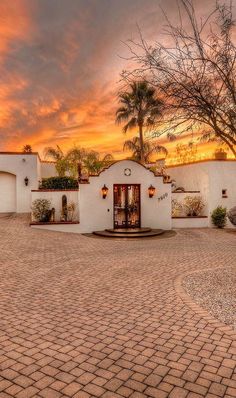 a white house with palm trees in the background and a red sky behind it at sunset