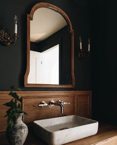 a bathroom sink sitting under a mirror next to a vase