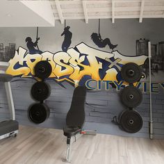 a gym room with various exercise equipment on the wall and graffiti painted on the wall