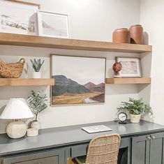 a desk with some plants and pictures on the wall