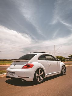 a white volkswagen beetle driving down the road