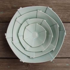 four white plates stacked on top of each other in a bowl, with the lids slightly open