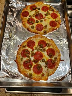 two pepperoni and olive pizzas on aluminum foil