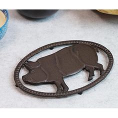 a metal pig brooch sitting on top of a table next to a bowl of fruit