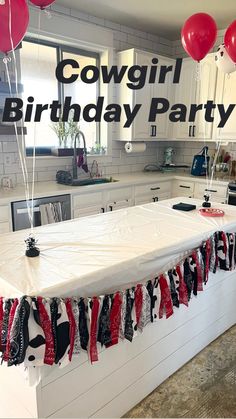 a kitchen counter with red and white balloons hanging from it's sides, along with an american flag table runner