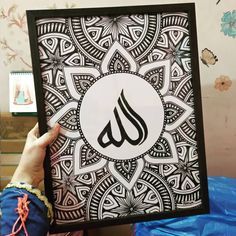 a person holding up a framed art piece with the word islamic written in arabic on it