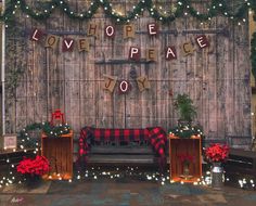 a wooden wall with christmas decorations and lights around it that says love peace to you