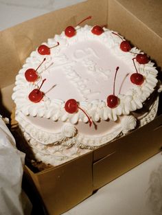 a cake in a box with cherries on it