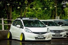 several cars parked in a parking lot with trees in the background and rain on the ground