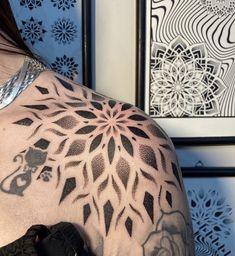 a woman with a tattoo on her shoulder and chest is standing in front of some art work