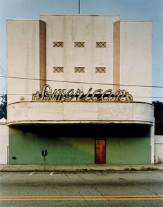 an old theater building with graffiti on it's side and the word american written in gold