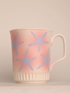 a pink and blue coffee cup with starfish designs on the inside, sitting on a white surface