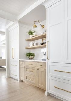 a kitchen with white cabinets and gold handles on the counters, along with wooden flooring