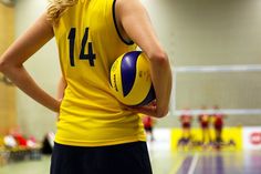 a woman holding a volleyball in a gym