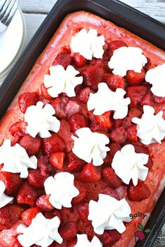 a square cake with strawberries and whipped cream on top is sitting on a plate