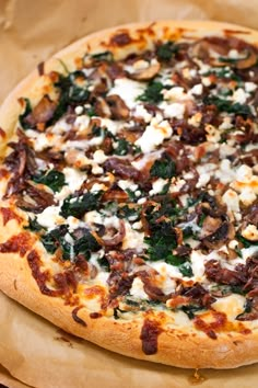 a pizza sitting on top of a wooden cutting board covered in cheese and toppings