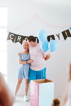 a man and woman hugging each other in front of balloons