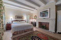 a bedroom with a bed, fireplace and rugs on the floor in front of it