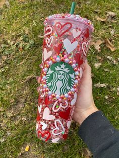 someone is holding up a starbucks cup with hearts on it and the lid covered in candy