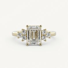 an emerald - cut diamond ring with three diamonds on the band and side stones in yellow gold