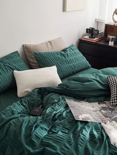 an unmade bed with green sheets and pillows