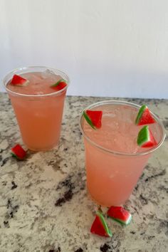 two glasses with watermelon garnish sit on a marble countertop next to each other