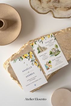 the wedding stationery is laid out on top of a rock and next to a teapot