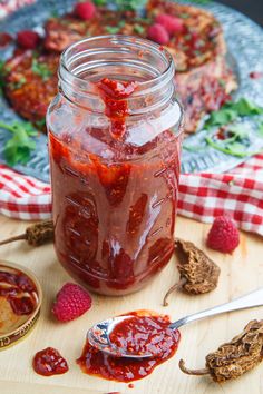 a jar filled with raspberry jam sitting on top of a wooden cutting board