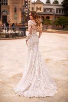 a woman in a white wedding dress standing on a brick walkway with her back to the camera