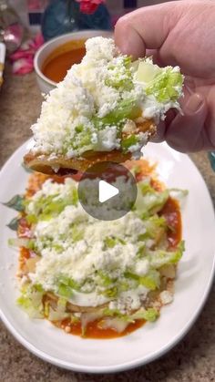 a person is holding up some food on a white plate with sauce and grated cheese