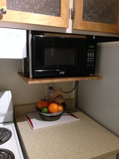 a microwave above a bowl of fruit on top of a counter