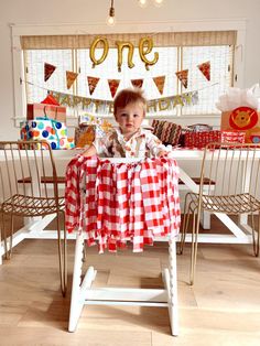 a young boy sitting at a table in front of a birthday cake and other decorations