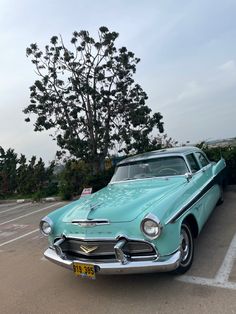 an old blue car parked in a parking lot