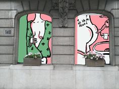 two flower boxes with flowers in them are on the side of a building, one is decorated with an image of a man and woman