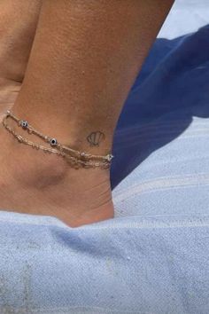 a woman's foot with a tattoo on it and a chain around the ankle