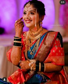 a woman in a red and blue sari with jewelry on her face, smiling at the camera