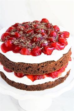 a chocolate cake with cherries and white frosting on a plate, ready to be eaten