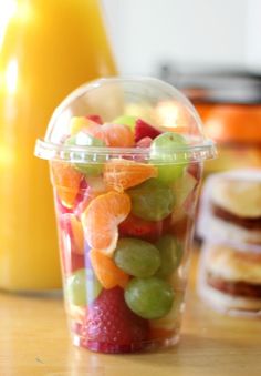 a plastic cup filled with fruit on top of a wooden table