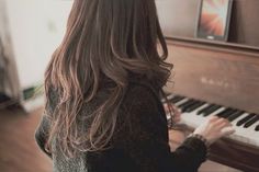 a woman sitting at a piano with long hair