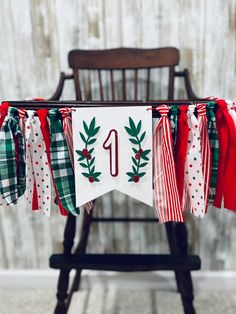 a number one banner hanging from a chair with christmas decorations on it and ribbon around the edges