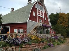 a red barn with lots of flowers growing on the side and steps leading up to it