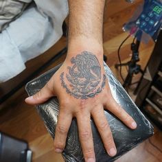 a man's hand with a tattoo on it and a mexican eagle in the middle